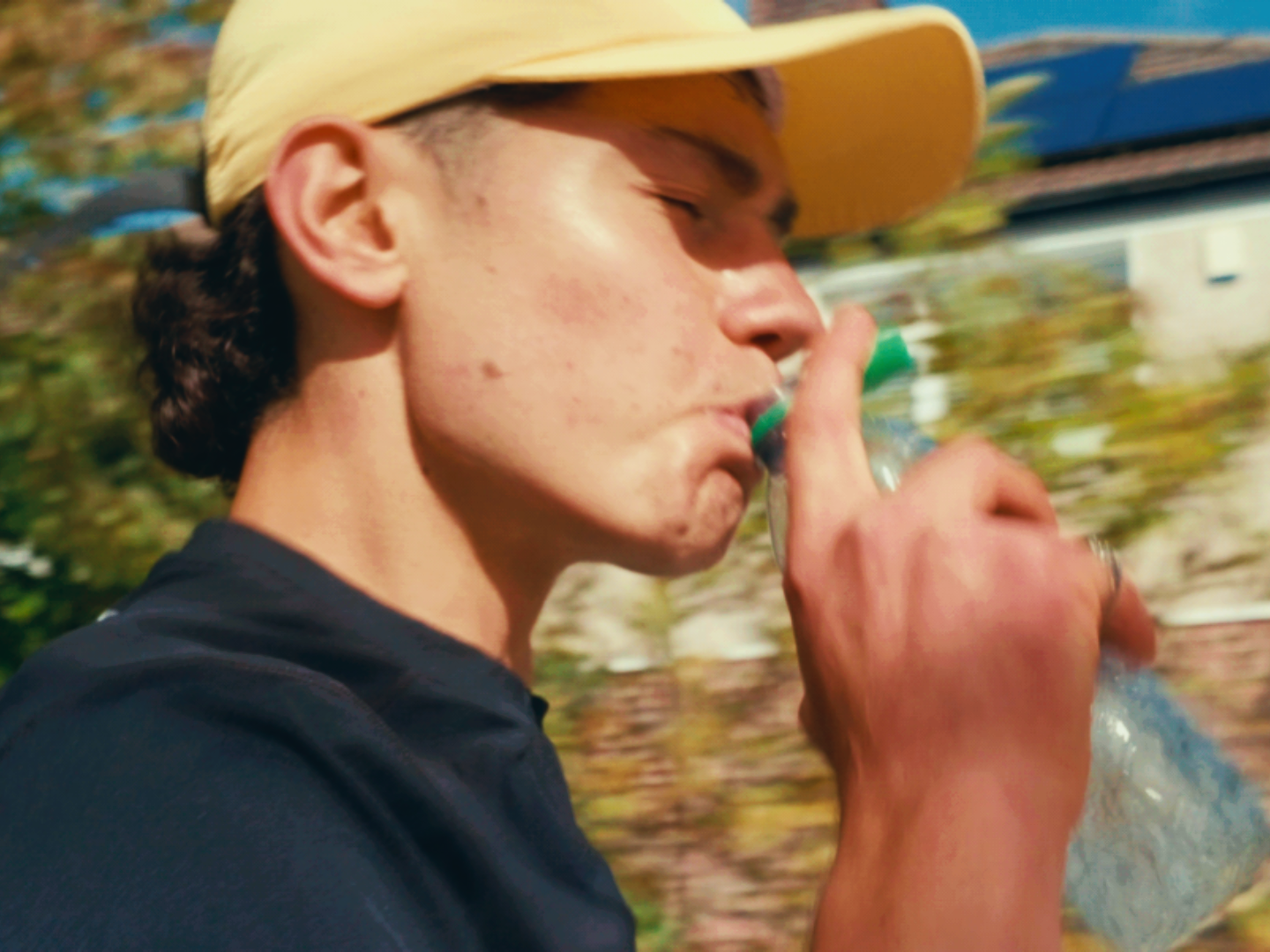 Perfil de un corredor con gorra clara bebiendo de una botella de agua